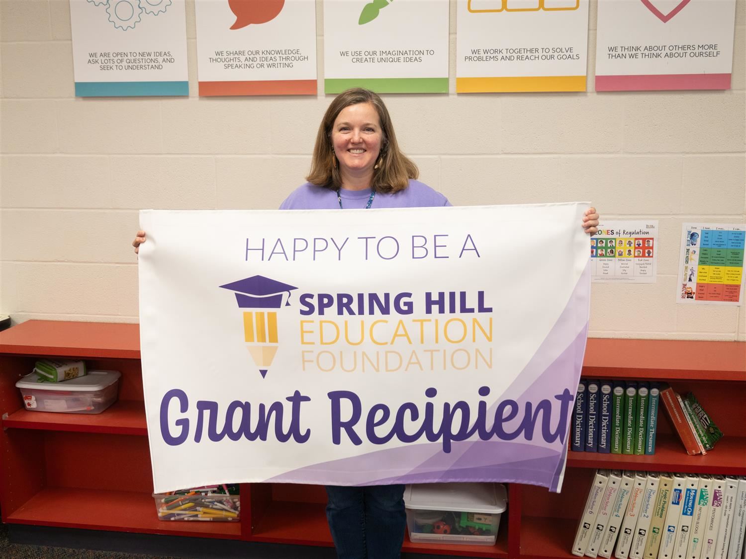 Rebecca Boomgaarden smiling with the "Happy to be a SHEF Grant Recipient" banner